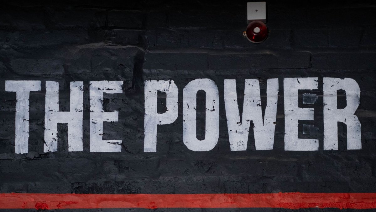 Close-up of 'The Power' graffiti on a dark wall, emphasizing strength and impact.
