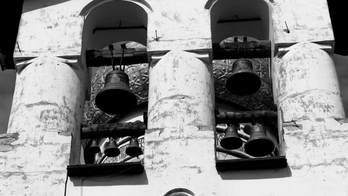 Monochrome image of an old bell tower featuring ancient bells.