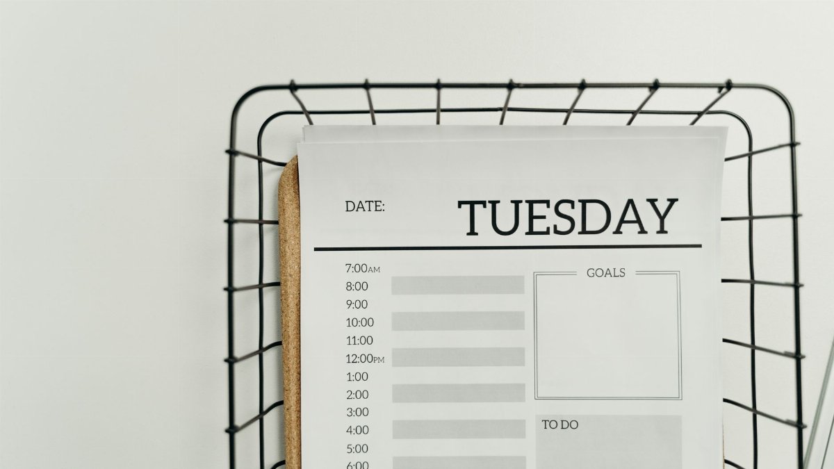 Top view of a minimalist Tuesday planner on a wire basket for organization and scheduling.