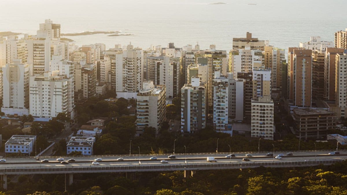 High-rise buildings overlooking the ocean with a highway, captured during sunset, in a coastal city.