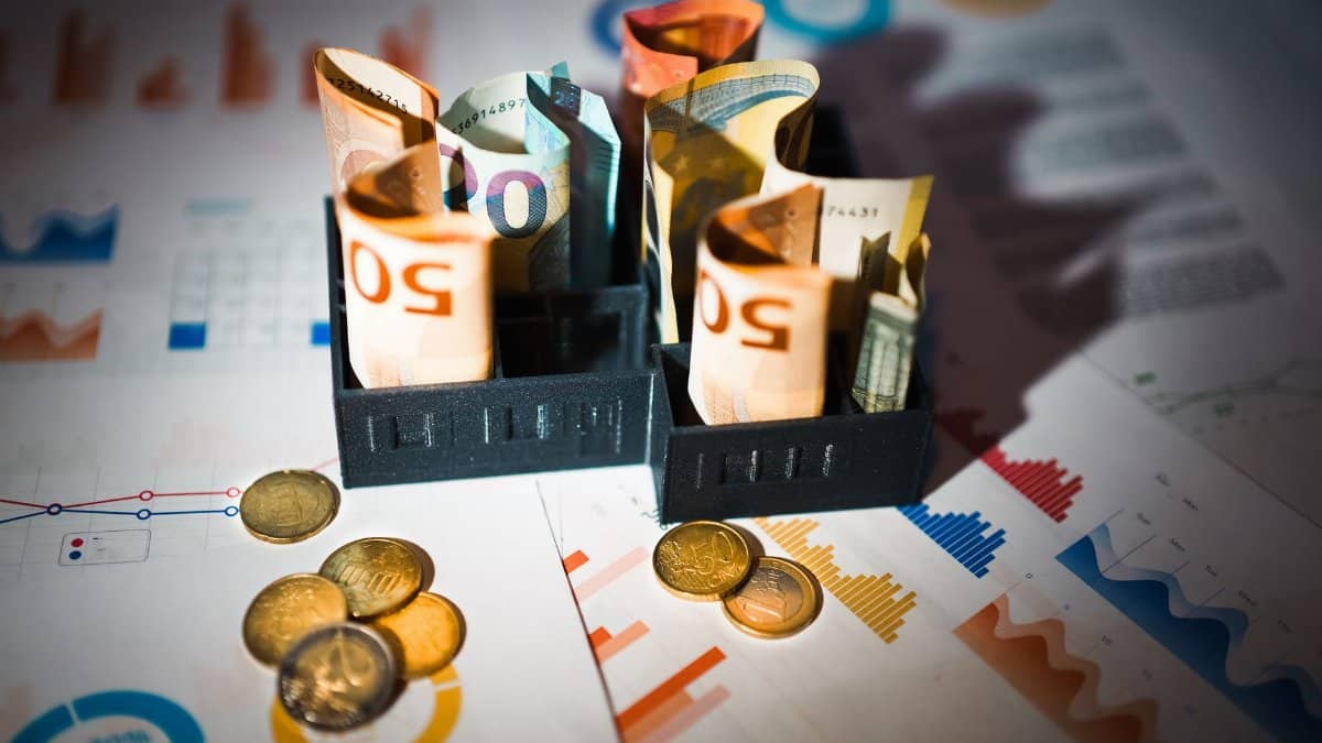A close-up of euro banknotes and coins on top of financial charts symbolizing investment and economic analysis.