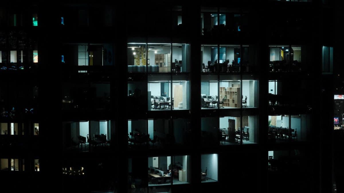 A nighttime view of a modern office building in Warsaw with illuminated interiors.