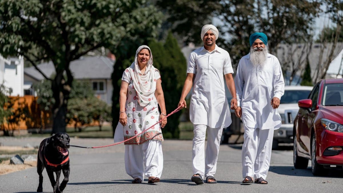 A family walking their dog on a sunny day, showcasing cultural attire and companionship.