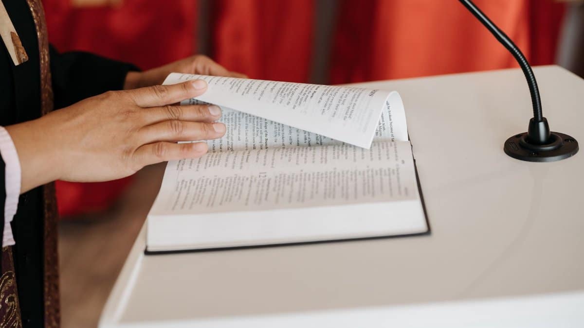 Close-up of a person reading the Bible at a church podium during a religious ceremony.