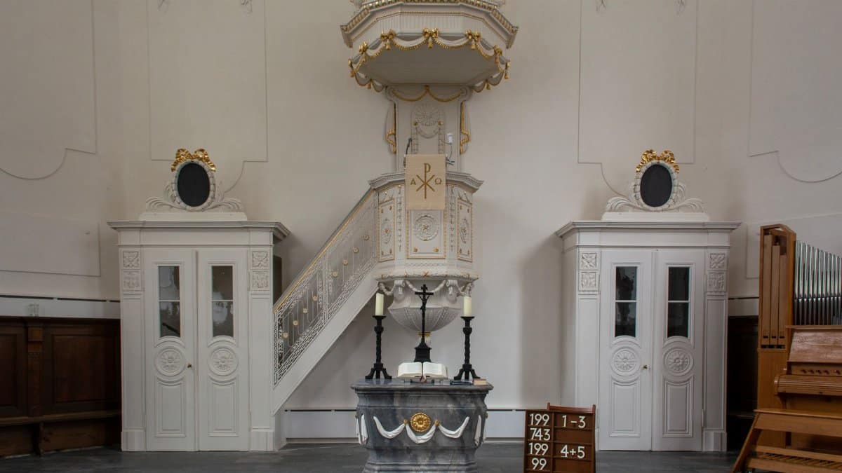Elegant church interior featuring a classic pulpit with intricate designs and organ.