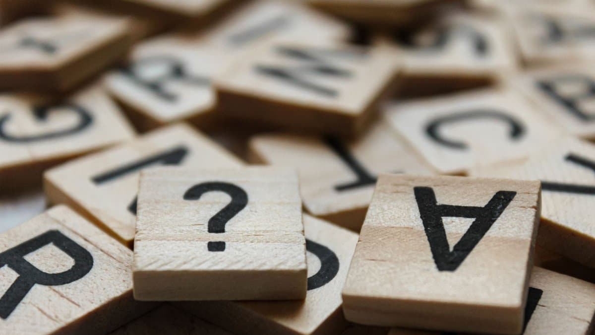 Close-up of wooden Scrabble tiles with letters and symbols, focusing on creativity and language.
