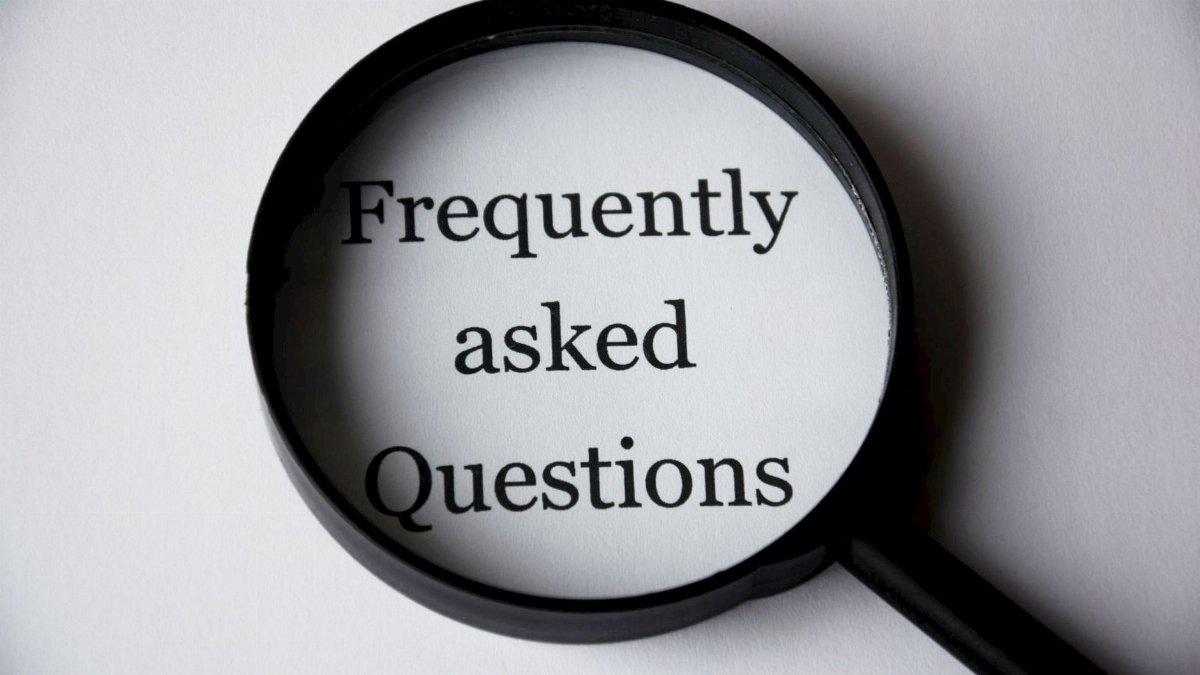 Close-up of a magnifying glass focusing on the phrase 'Frequently Asked Questions'.