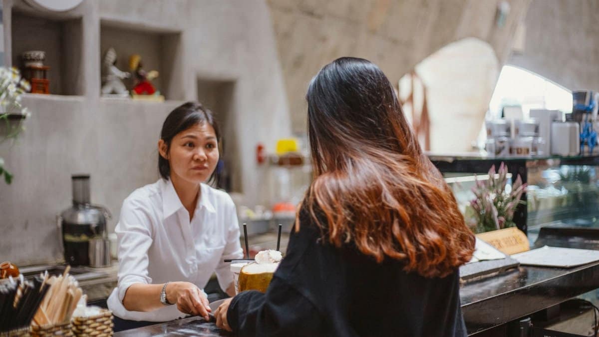 A barista interacts with a customer at a trendy café counter, showcasing customer service.