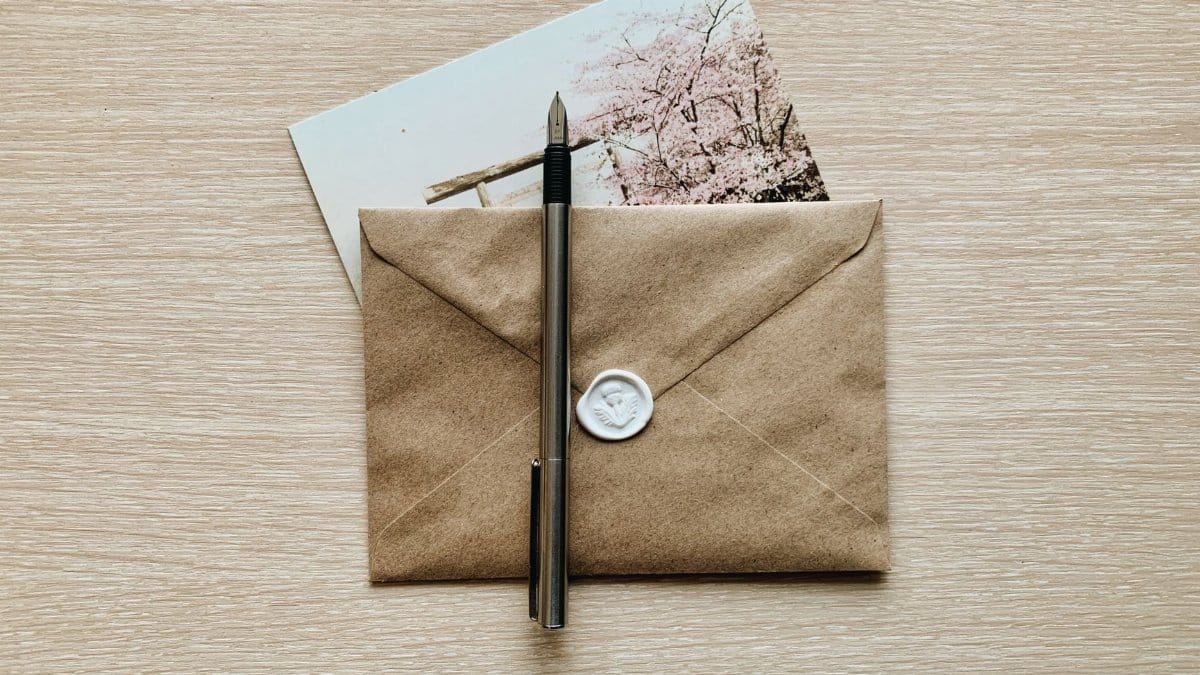 A classic brown envelope with a wax seal and pen atop a wooden desk, evoking a vintage feel.