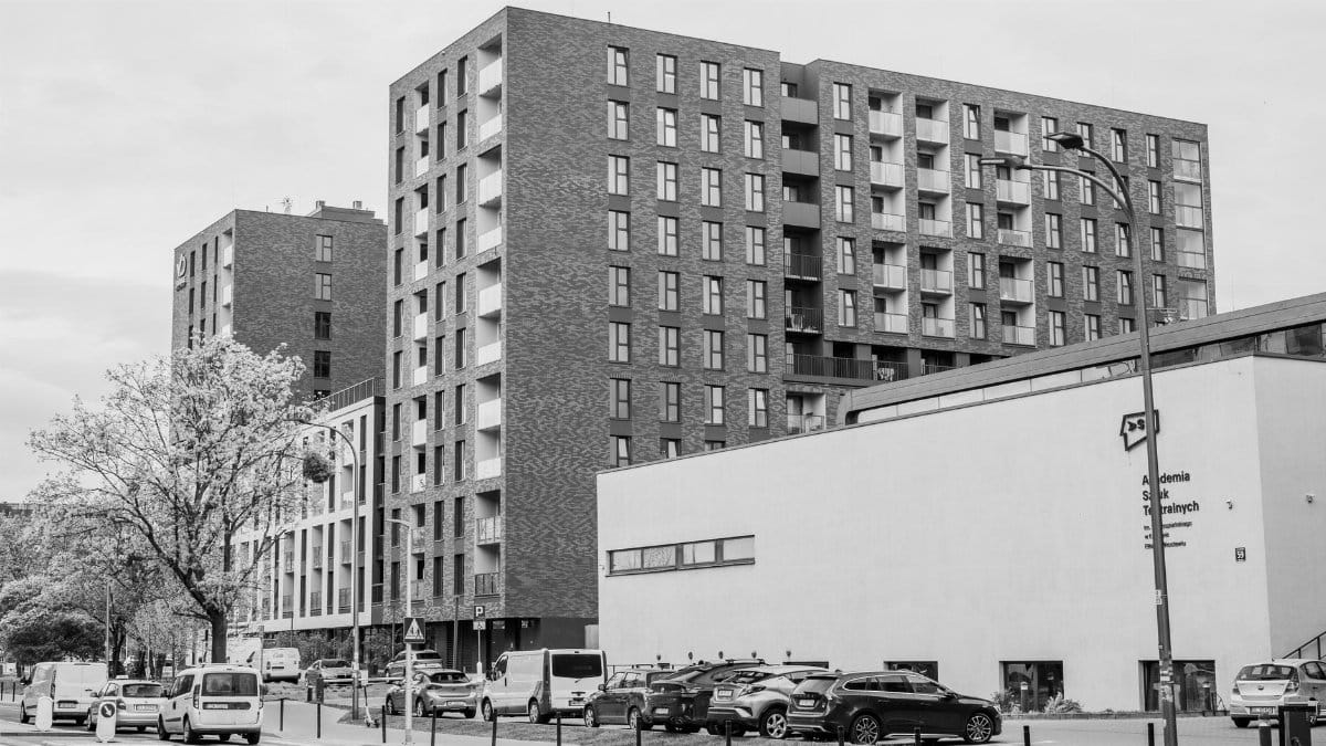 Black and white urban view showcasing modern apartment buildings and city life.
