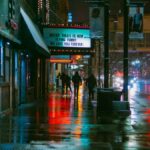 Rainy night scene in downtown Minneapolis with colorful reflections and city life vibes.