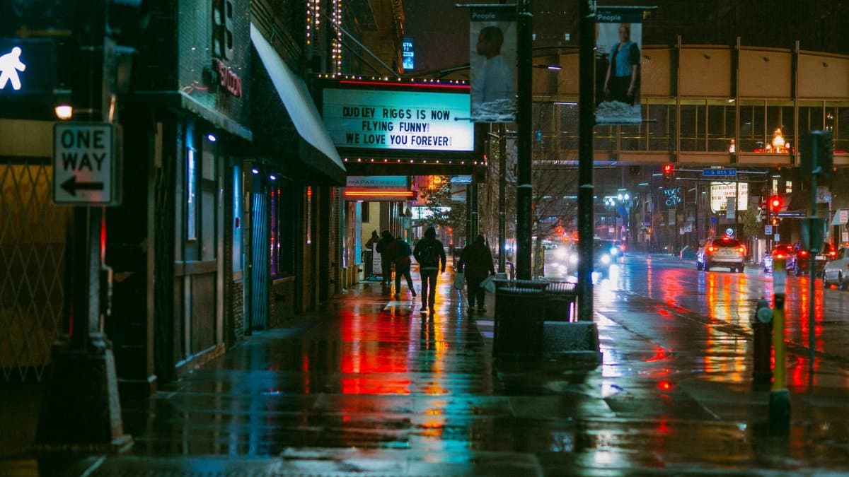 Rainy night scene in downtown Minneapolis with colorful reflections and city life vibes.