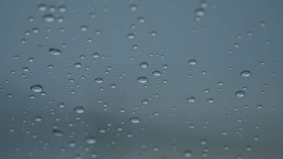 Close-up view of rain droplets on glass, creating a peaceful and serene scene.