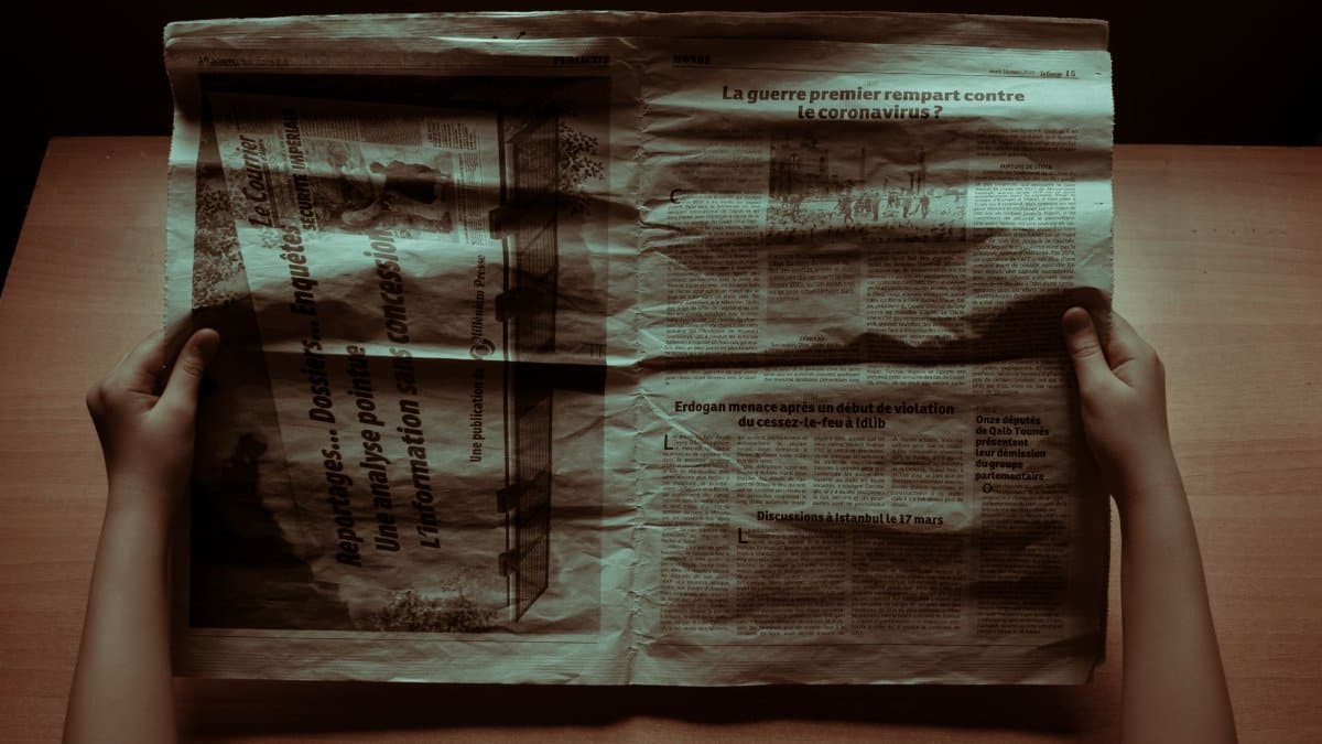A person reading a retro newspaper at a desk in moody lighting, evoking nostalgia.