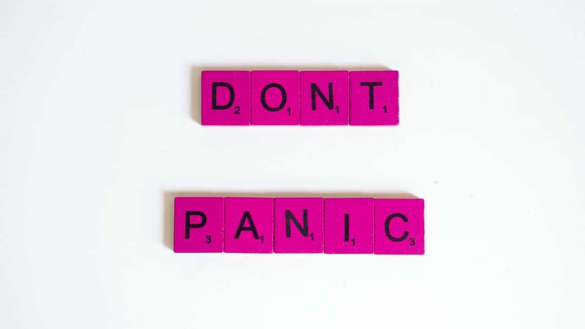 Pink Scrabble tiles spell out 'Don't Panic' on a white background.
