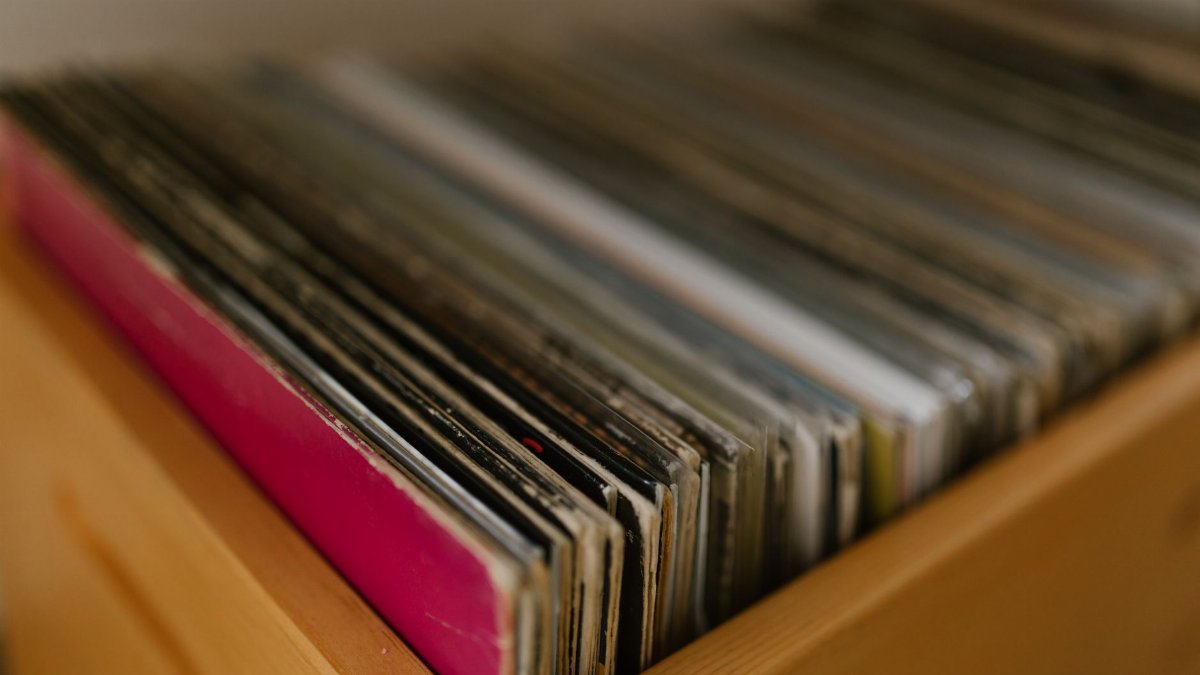 A collection of vintage vinyl records stored in a wooden shelf, showcasing a blurred background.