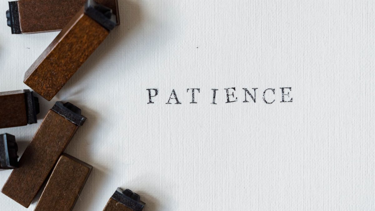Letterpress 'Patience' on white surface with wooden blocks for a vintage feel.
