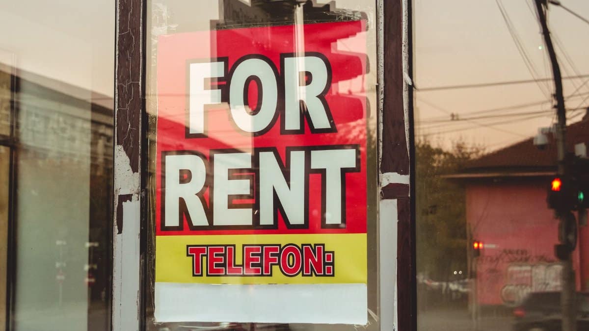 Reflection of a cityscape on a window with a 'For Rent' sign and sunset glow.