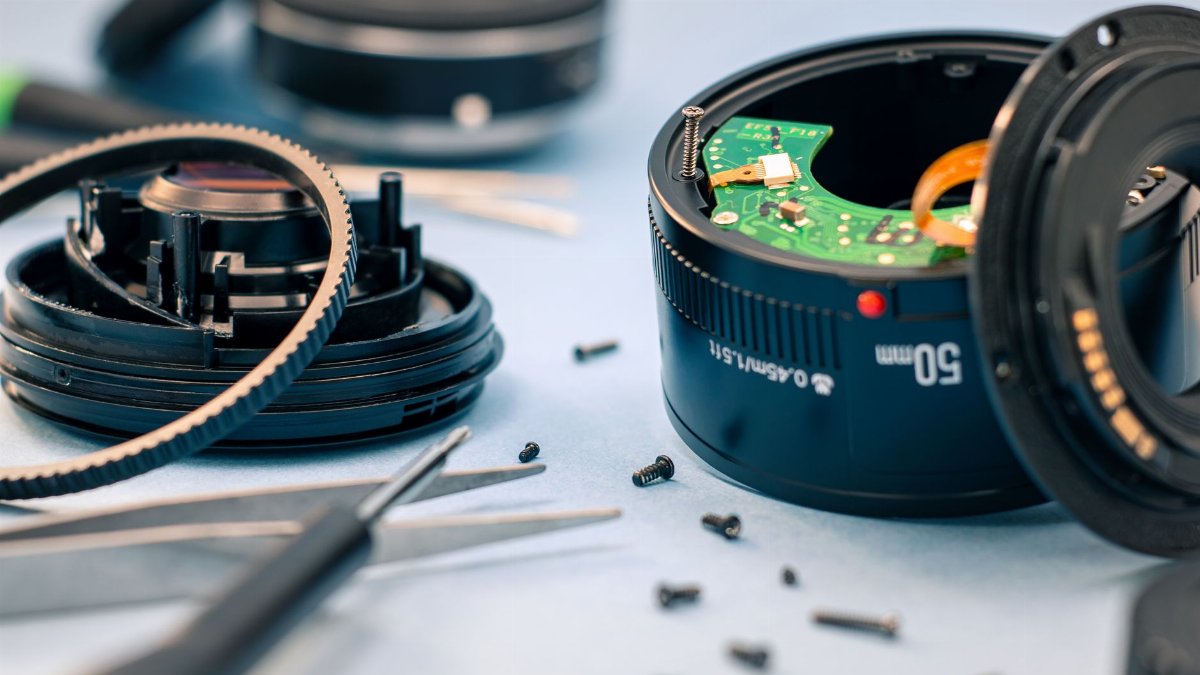 Close-up of camera lens components with tools, showcasing detailed repair and maintenance process.