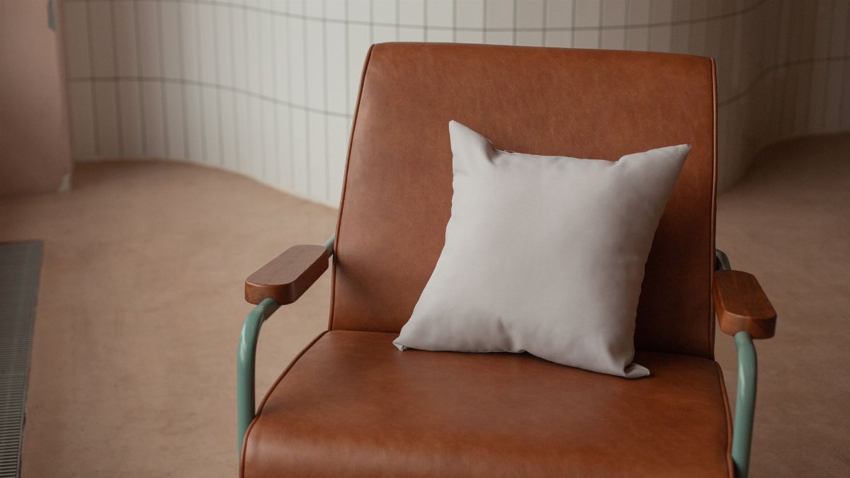 A stylish brown leather chair with a light cushion in a modern indoor setting, showcasing minimalistic design.