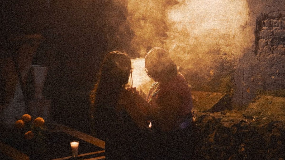 Two people perform a mystical evening ritual with candlelight and smoke outdoors.