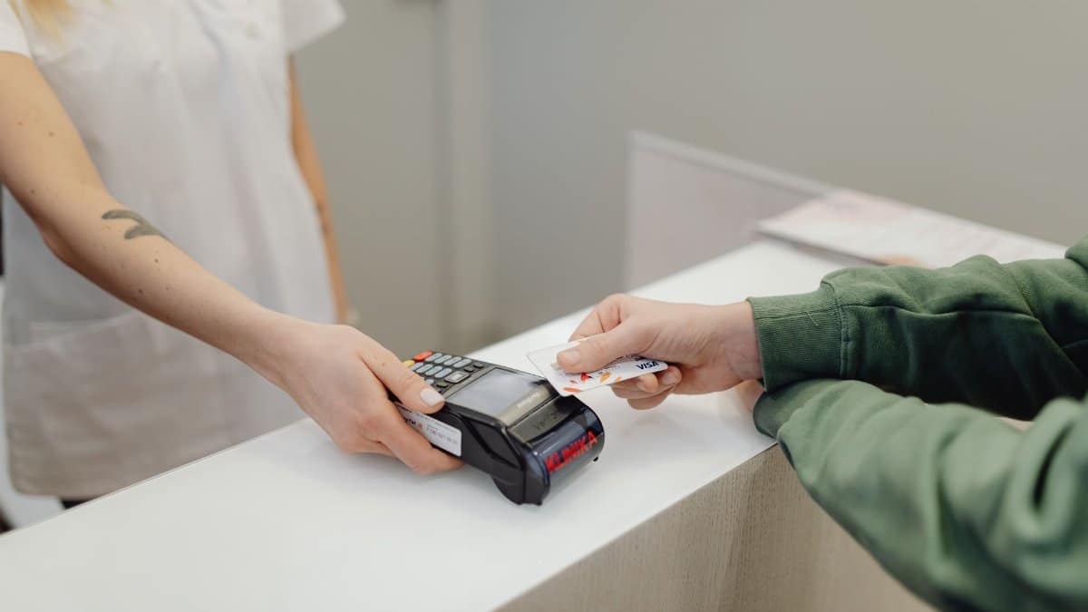 Person using a bank card for contactless payment at a modern checkout counter.