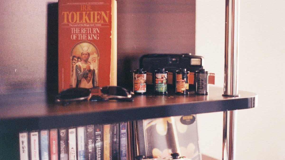 A vintage scene featuring a J.R.R. Tolkien book, sunglasses, camera film rolls, and a bookshelf.