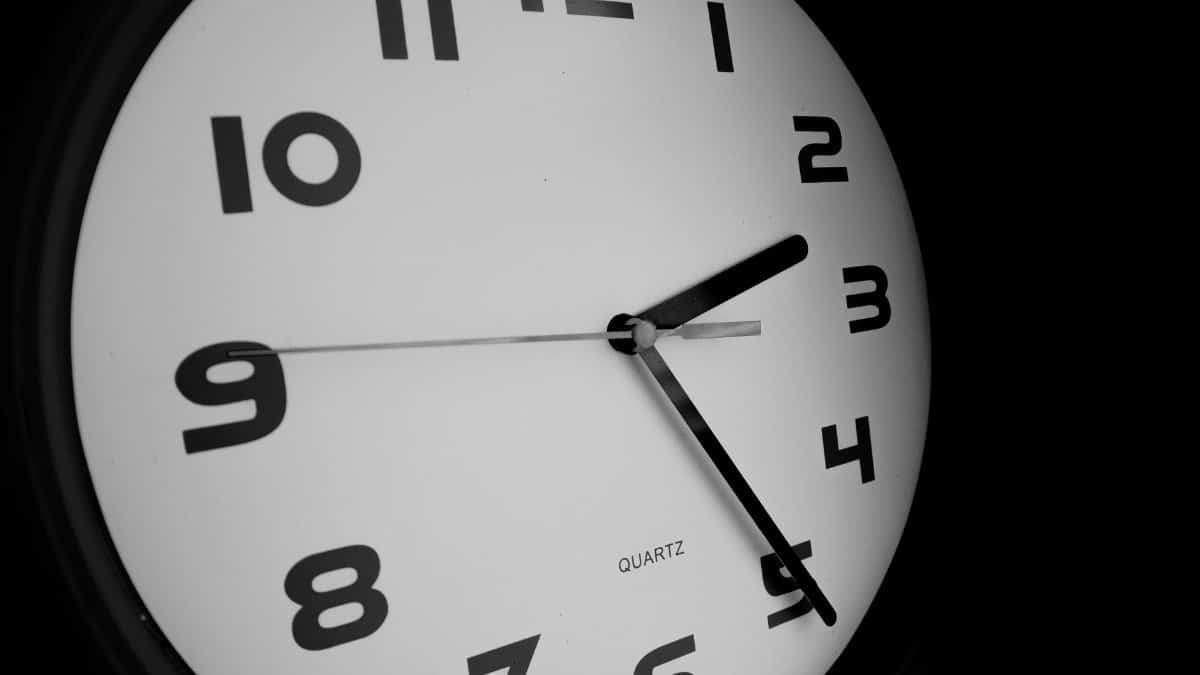 Black and white close-up of a wall clock showing nine o'clock.