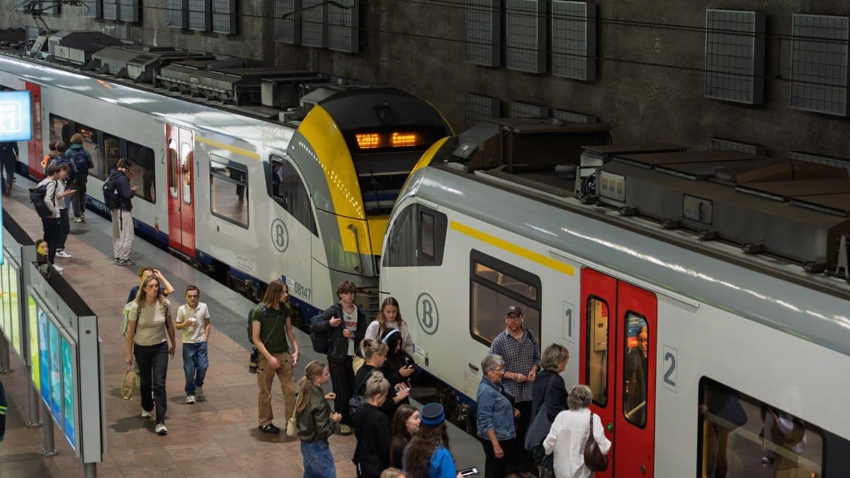 A crowded platform at a train station with people boarding and exiting trains.