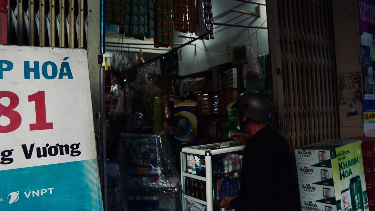 A local convenience store in Vietnam with a customer browsing products.