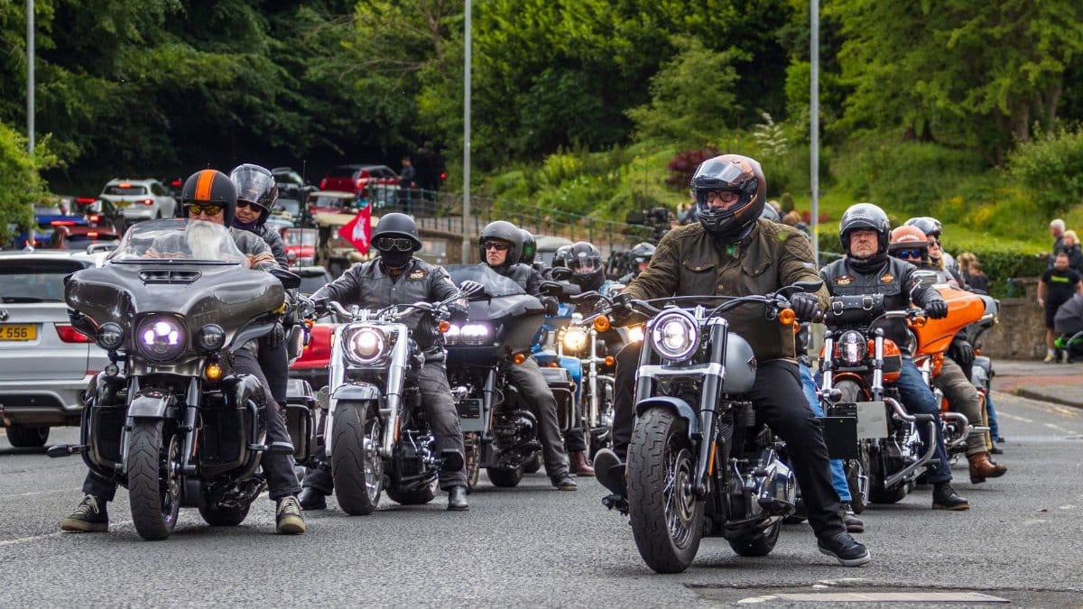 Group of motorcyclists riding through Morpeth, England, on a clear day, showcasing biker culture.
