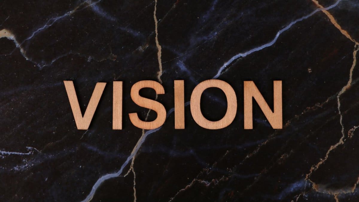 Wooden letters spelling 'Vision' on a dark marble surface, symbolizing clarity and goals.