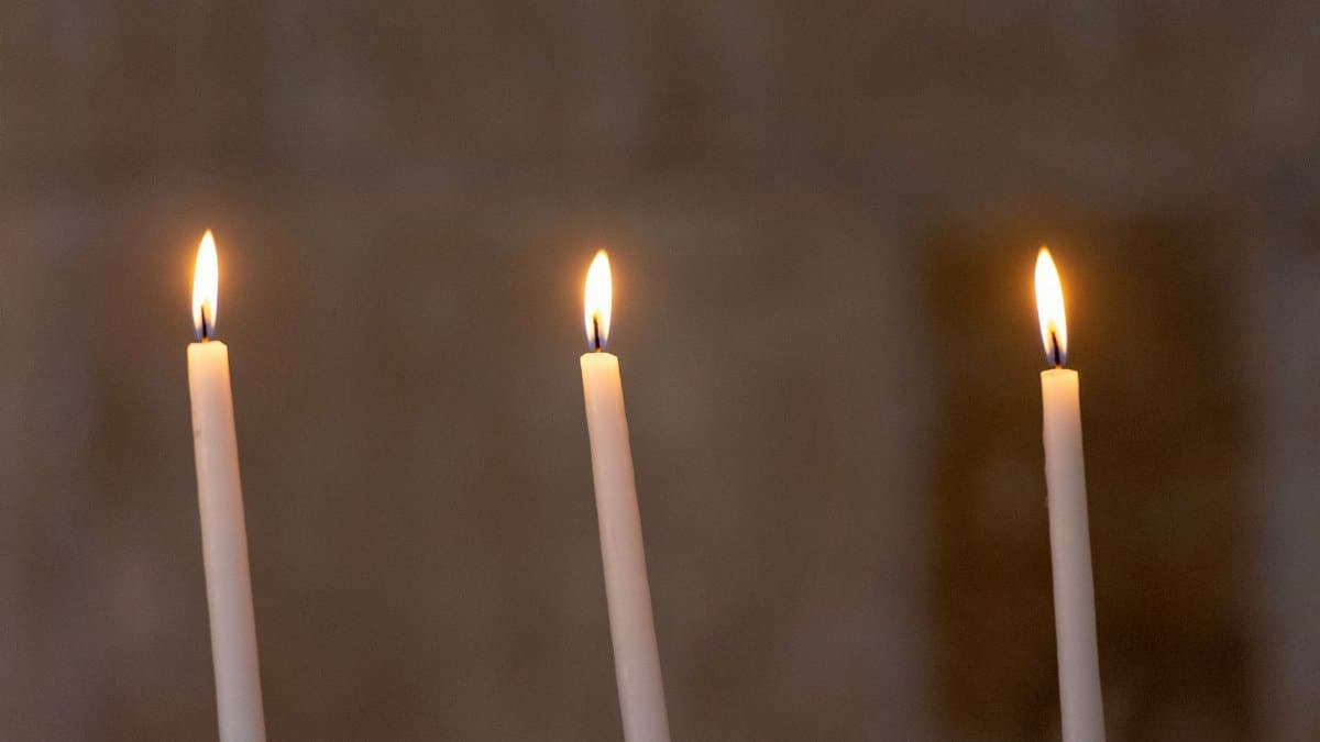 Three lit candles against a soft, warm background create a tranquil scene, perfect for meditation.