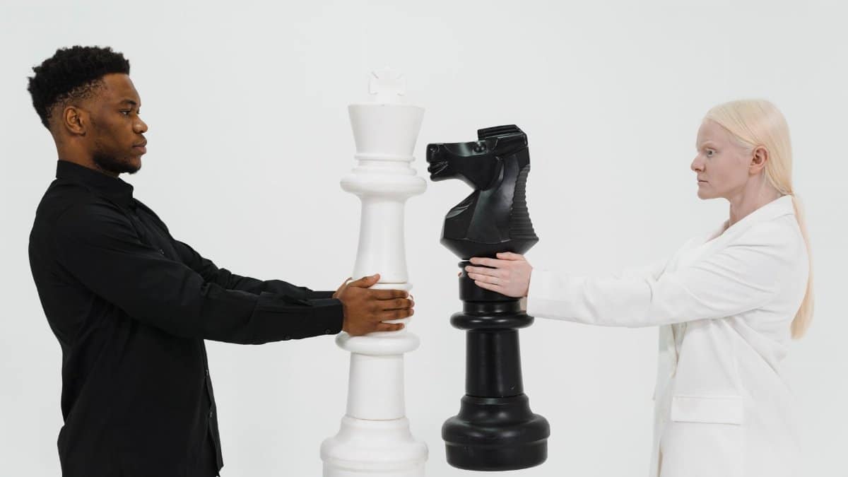 Two individuals holding giant chess pieces symbolizing strategy and competition.