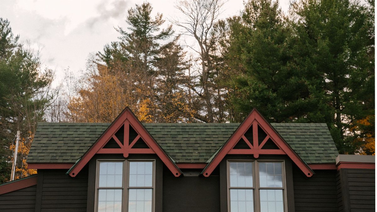 Windows with glazing bars under roof of cozy traditional residential house surrounded by trees on cloudy autumn day