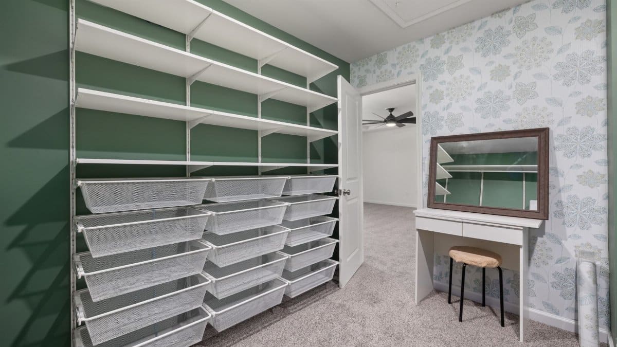 Spacious walk-in closet with built-in shelving, storage bins, and a vanity desk with mirror.