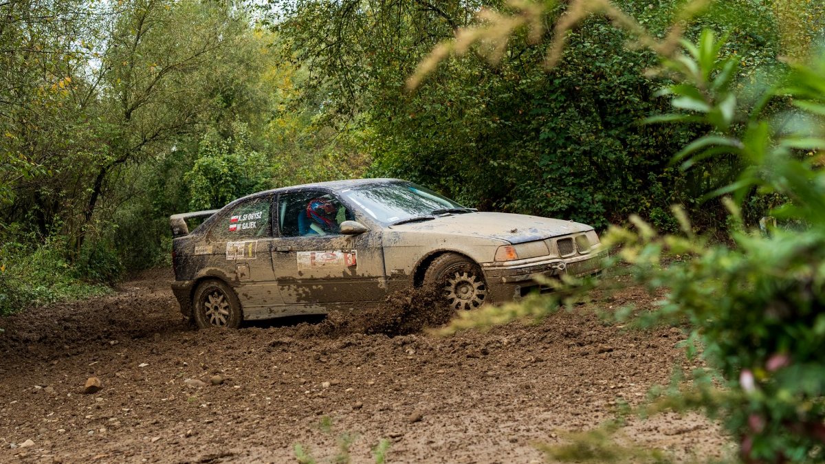 Exciting off-road rally car navigating a muddy forest path, showcasing speed and adventure.