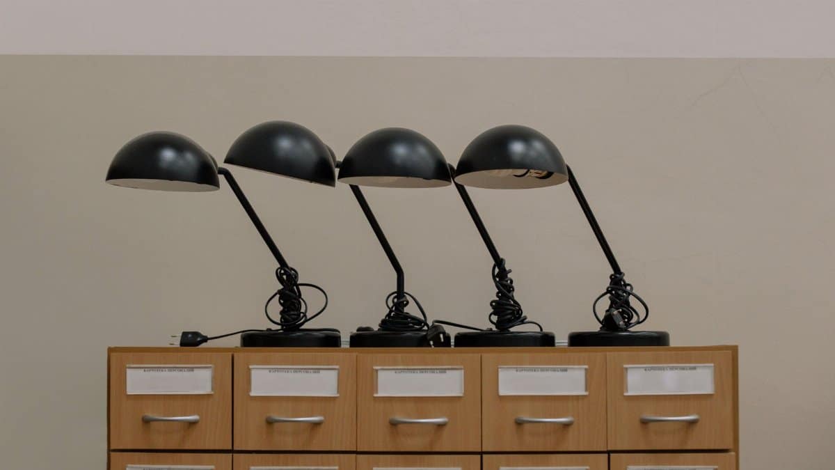 Four black retro desk lamps on a wooden cabinet, embodying minimalist design in an elegant interior.