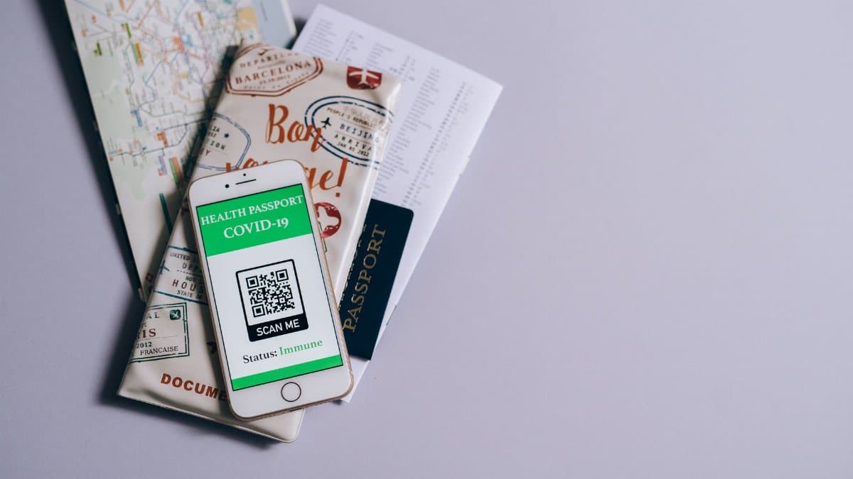 A health passport for COVID-19 displayed on a smartphone alongside travel documents.