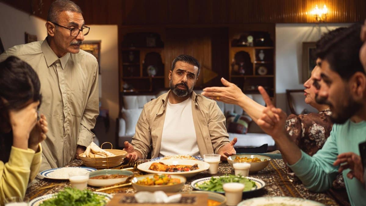 A family engages in a lively discussion around a dinner table filled with dishes.