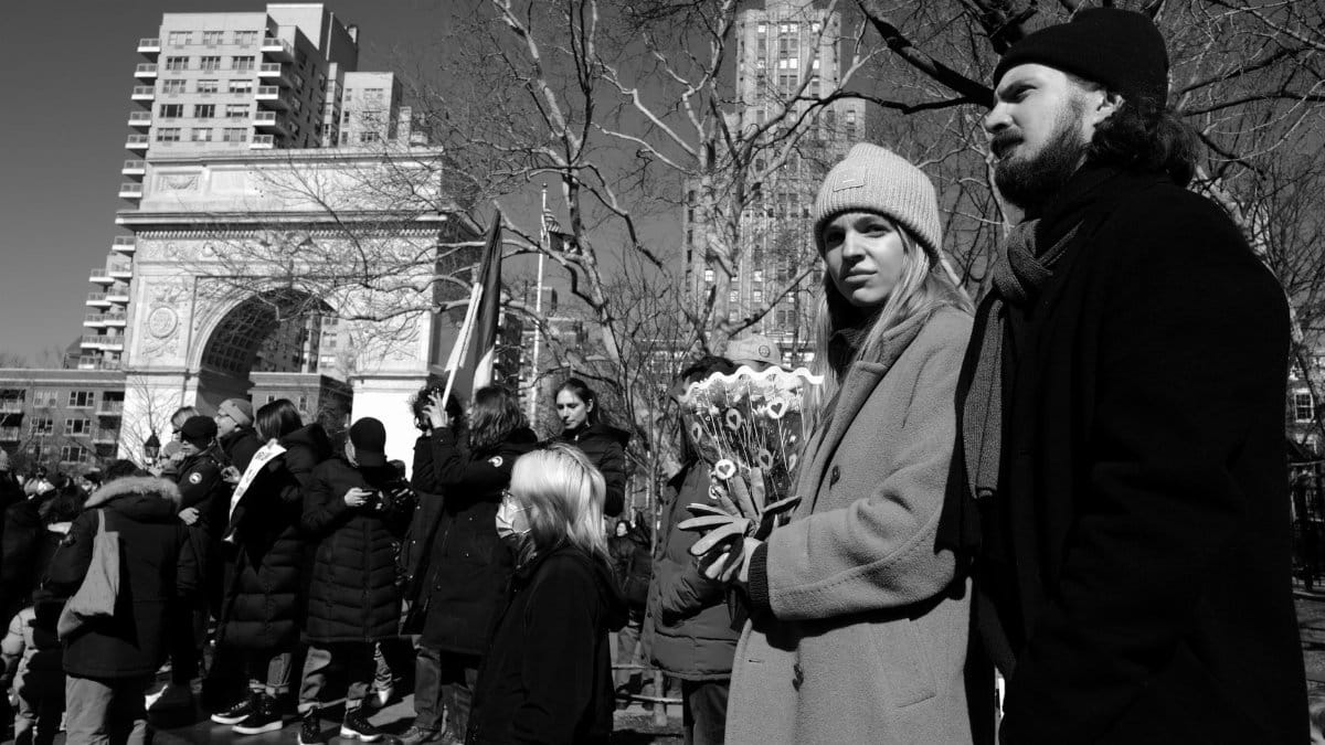 Black and white scene of people in winter coats at Washington Square Park, New York.