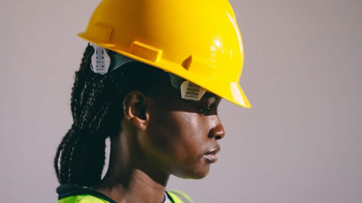 Side view of a woman engineer wearing a yellow hard hat and reflective vest, showcasing safety in engineering.