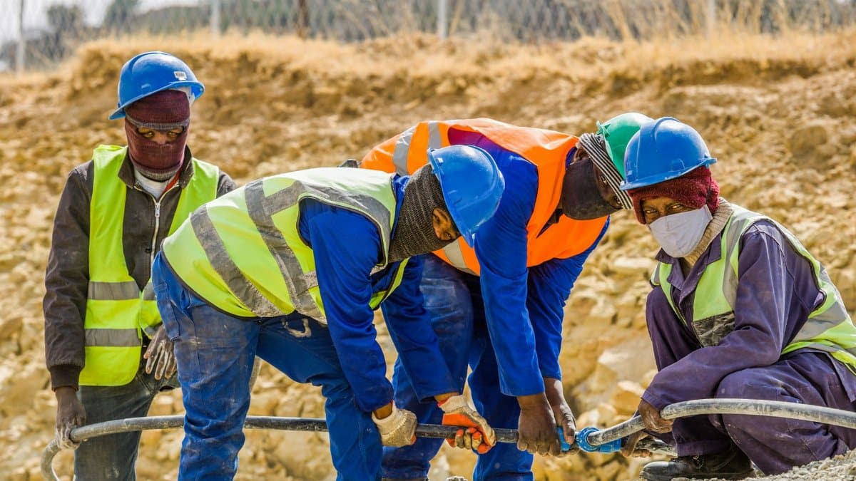 Team of construction workers in safety gear collaborating on a project outdoors in South Africa.