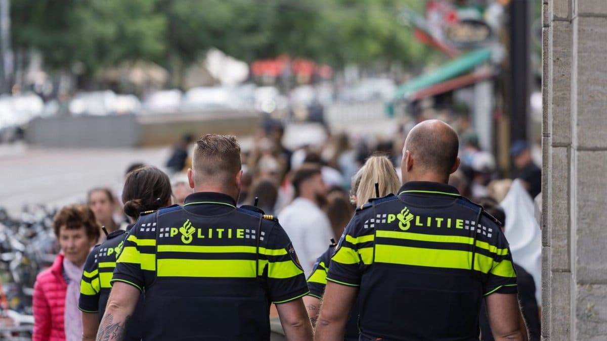 Dutch police officers walking on a crowded urban street, maintaining public safety.