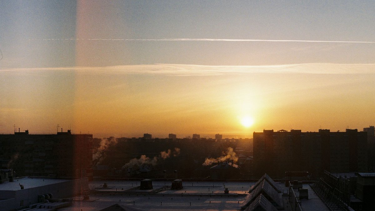A breathtaking view of a city skyline silhouette during sunrise with warm hues and a serene atmosphere.