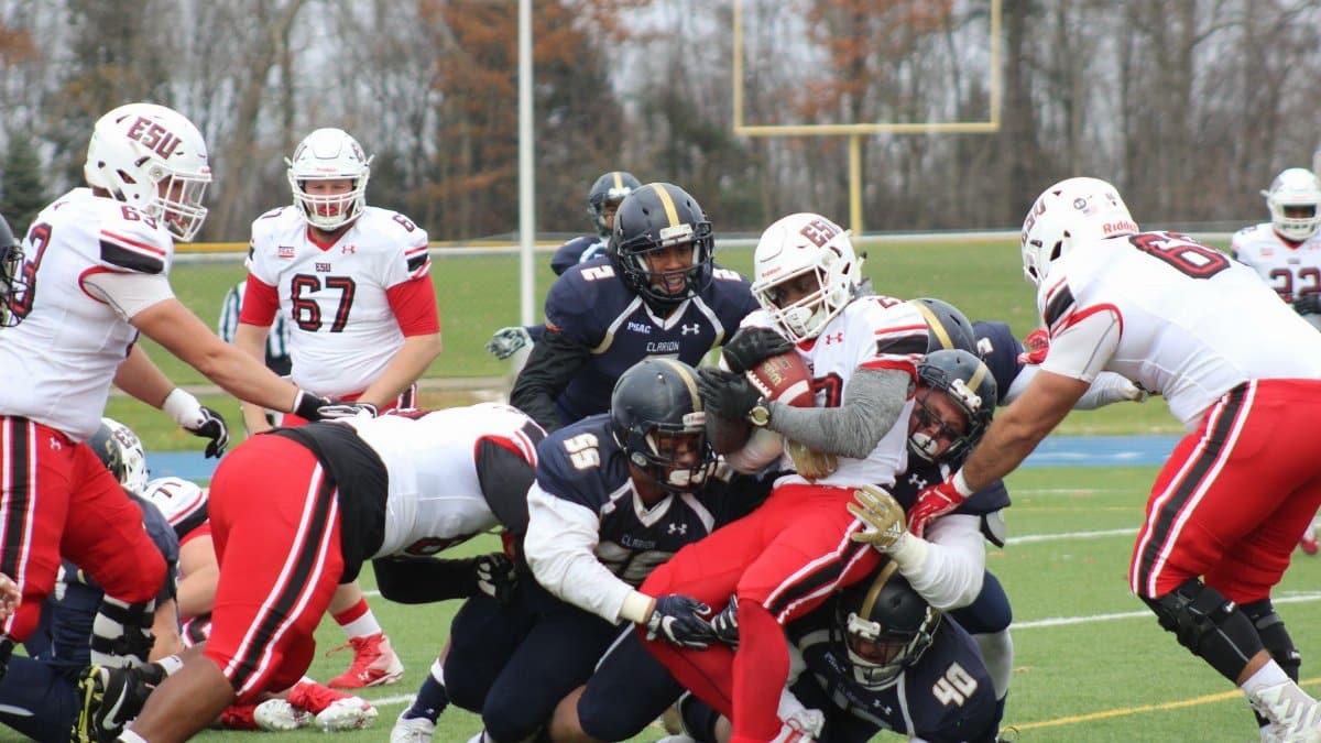 College football players in action during an intense tackle on the field showcasing teamwork and competition.
