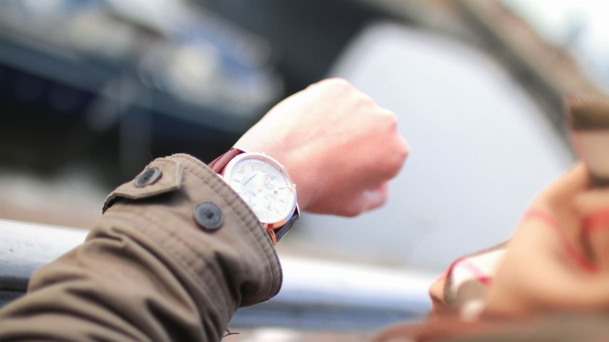 A person checks their wristwatch in a hurried outdoor setting, emphasizing time management.