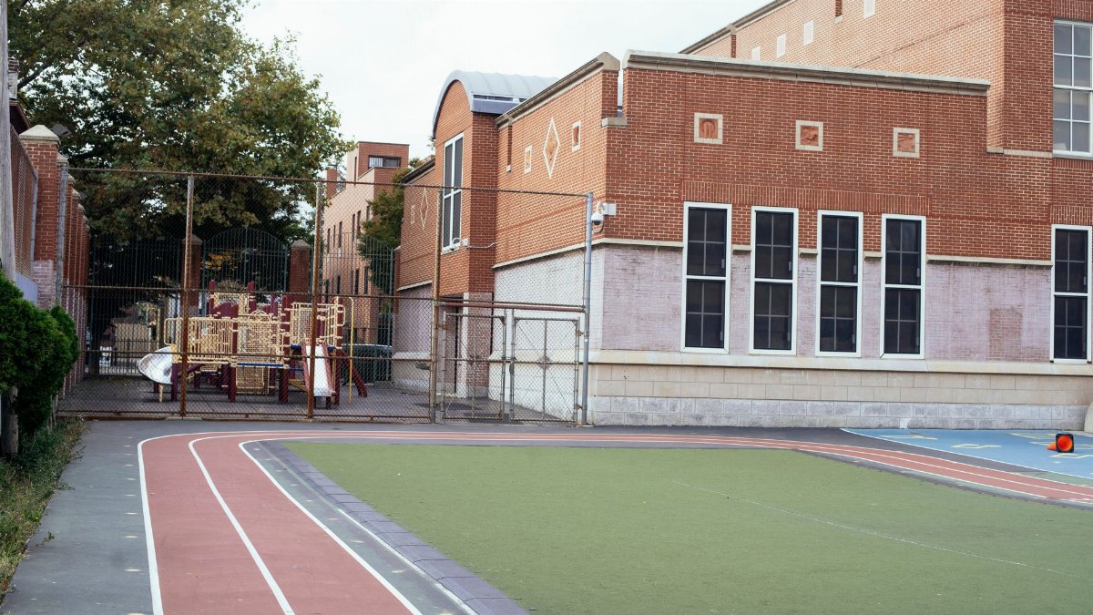 Exterior of contemporary school building made of red brick with empty sports ground