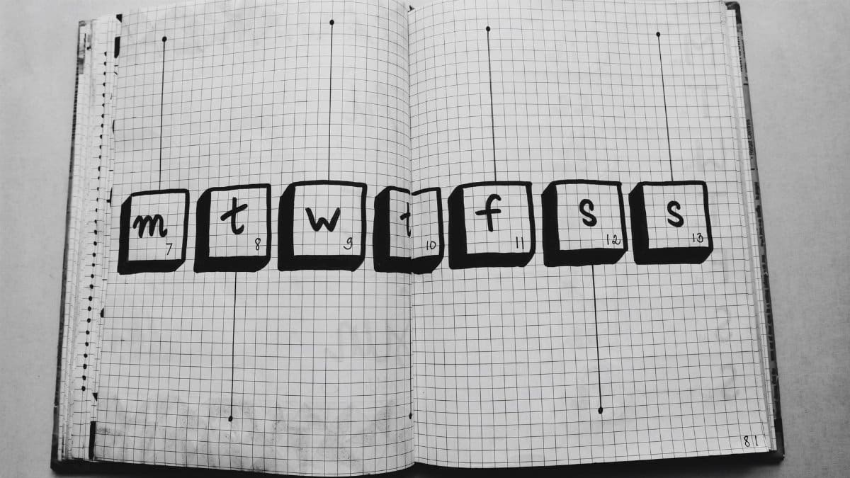 Open grid notebook with days of the week drawn inside boxes, perfect for planners.