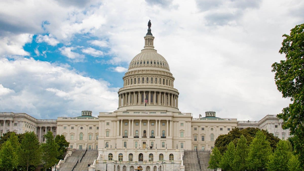 View of United States Capitol with neoclassical architecture against a cloudy sky in Washington D.C.